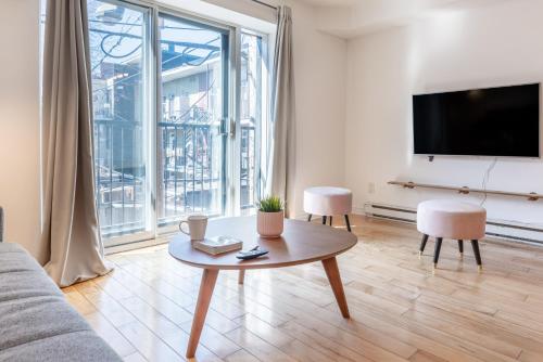 a living room with a table and a large window at Alywin Apartments in Hochelaga in Montréal