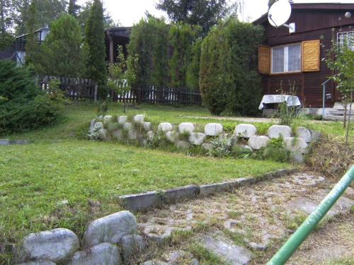 a yard with a stone fence in front of a house at Holiday home in Leanyfalu - Donauknie 35231 in Leányfalu