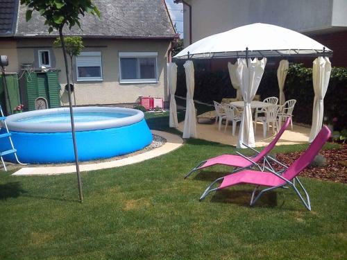 バラトンボグラールにあるTwo-Bedroom Holiday home with Pool in Balatonboglar/Balaton 18176のプールとピンクの椅子とパラソルが備わる庭
