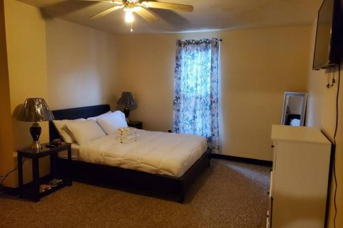 a bedroom with a bed with a ceiling fan and a window at Nice and cozy home for a business or family stay. in Johnstown