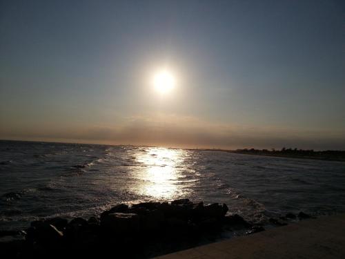 a sun setting over the water on a beach at Hotel Marea in Grado
