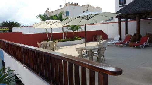 a balcony with tables and chairs and umbrellas at Tonsupa Beach in Tonsupa