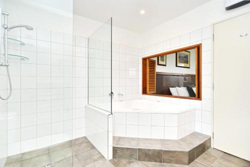 baño blanco con bañera y ventana en High Country Villa 250 - Terrace Downs, en Windwhistle