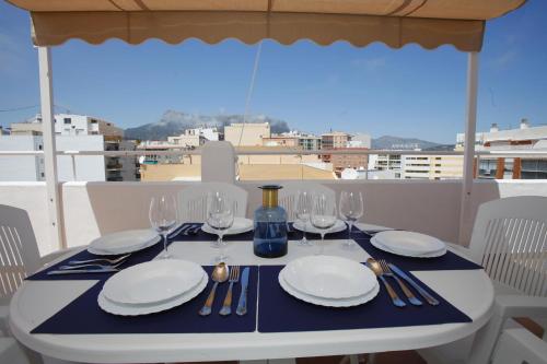 une table avec des assiettes et des verres à vin sur un balcon dans l'établissement Pondarosa Penthouse 56 - Costa CarpeDiem, à Calp