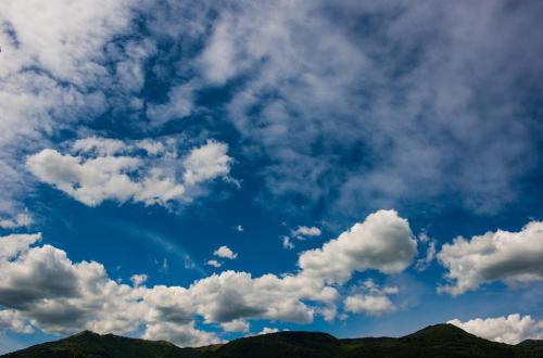 a blue sky with white clouds and green mountains at Hotel Helvetia in Lezzeno