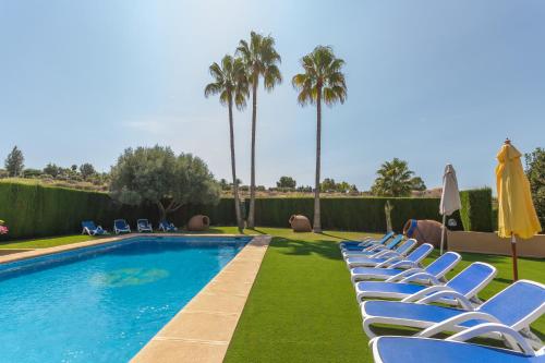 - une rangée de chaises longues à côté de la piscine dans l'établissement Villa Benimarco - Costa CarpeDiem, à Teulada