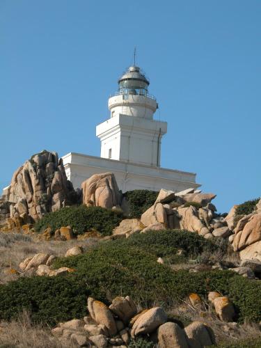 a lighthouse on top of a hill with rocks at Hotel Moderno in Santa Teresa Gallura