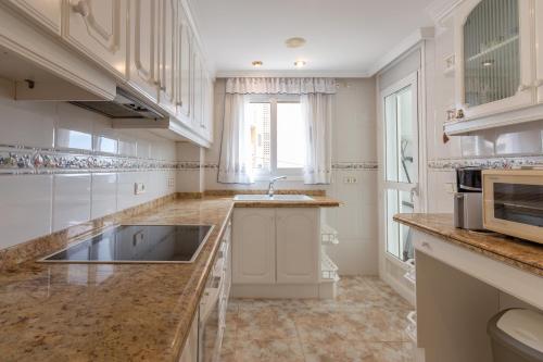 a large kitchen with a sink and a microwave at Apartamento Joya I - Costa CarpeDiem in Calpe