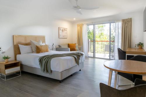 1 dormitorio con cama, mesa y balcón en Noosa Heads Motel en Noosa Heads