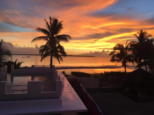 a sunset from a resort with a pool and palm trees at Maykenn Beach in Bantayan Island