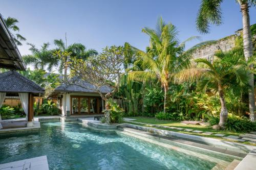 una piscina en el patio trasero de una casa con palmeras en Maya Sayang Seminyak, en Seminyak