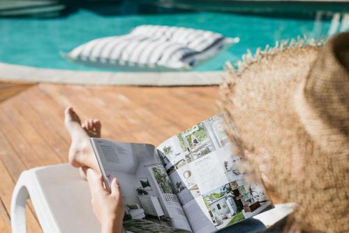 uma pessoa lendo um livro enquanto sentado em uma cadeira em Noosa Heads Motel em Noosa Heads