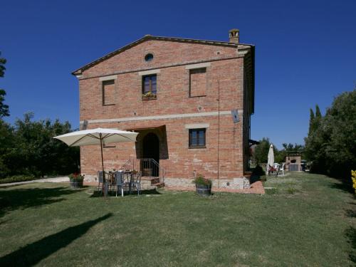 een groot bakstenen gebouw met een tafel en een paraplu bij Belvilla by OYO Farmhouse in Tuscany with Garden in Castelnuovo Berardenga