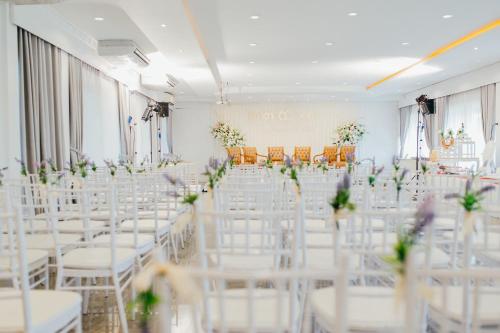 a room with white chairs and tables and flowers at โรงแรมเกียรตินคร (Kiatnakhon Hotel) in Nakhon Si Thammarat