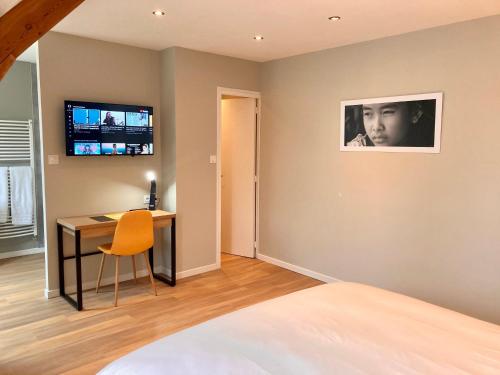 a bedroom with a desk and a television on the wall at OXXOTEL in Valognes