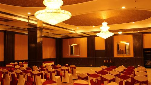 a banquet hall with red and white chairs and chandeliers at Regenta Inn Jaipur, Adarsh Nagar in Jaipur