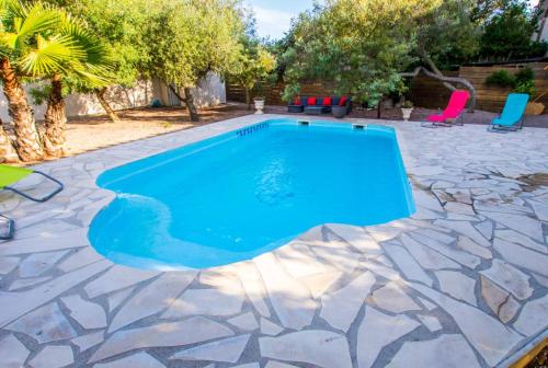a swimming pool with blue water on a stone patio at Villa Napoléon Piscine&Jacuzzi in Le Somail