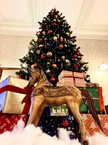 a christmas tree with a toy horse in front of a christmas tree at Hotel Livio in Brescia