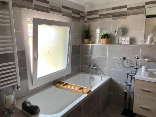 a bathroom with a tub and a window and a sink at Villa Spa de l’Ajoie in Cornol