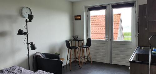 a room with three stools and a door with a window at Ut Endt Vlieland in Oost-Vlieland