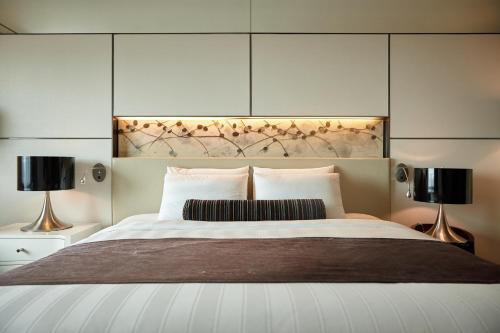 a bedroom with a large bed with two lamps at Lotte Hotel Busan in Busan