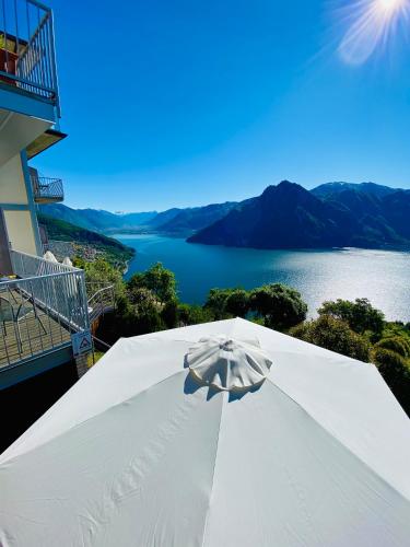 a white umbrella on a balcony with a view of a lake at Esprit D'Hotel Panoramico in Fonteno