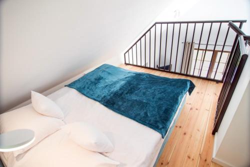 a white bed with a blue blanket next to a staircase at Kameralny domek Kazimierzówka in Kazimierz Dolny