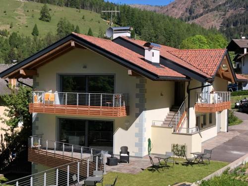 a house with a red roof and a balcony at B&B Le Stagioni di Stava in Tesero