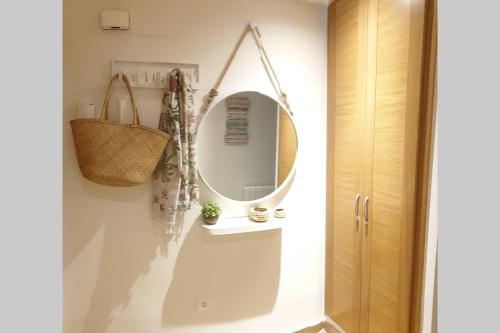 een badkamer met een spiegel en een mand aan de muur bij El paraiso de Anita in Benicàssim