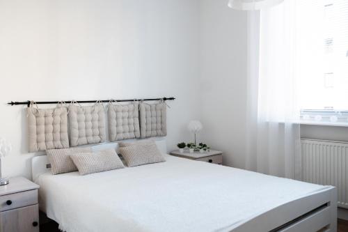 a white bedroom with a large white bed with pillows at Apartament dwupokojowy in Świnoujście