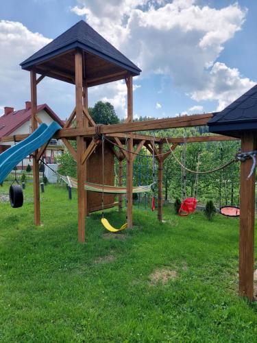 a playground with a wooden gazebo and swings at Go2Beskidy apartament ODSAPKA in Sękowa