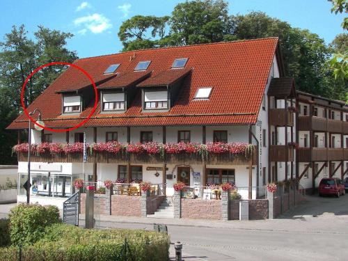 un edificio con techo rojo con flores. en Pension Schneider, Ferienwohnung, en Bad Gögging