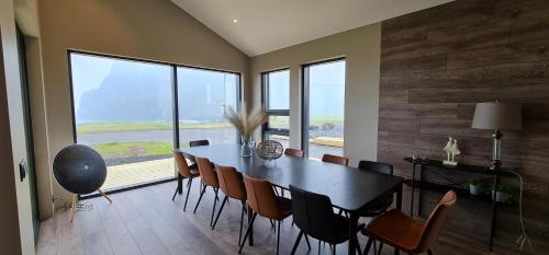 a dining room with a table and chairs and windows at Luxury Ocean Villas in Vestmannaeyjar