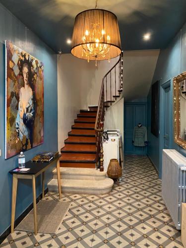 a hallway with a staircase with a painting and a chandelier at La maison Gerval in Bédoin