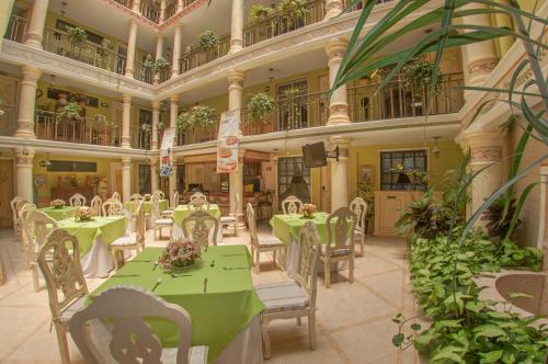 ハラパにあるVilla las Margaritas Plaza Cristalの緑のテーブルと椅子が並ぶ建物内のレストラン