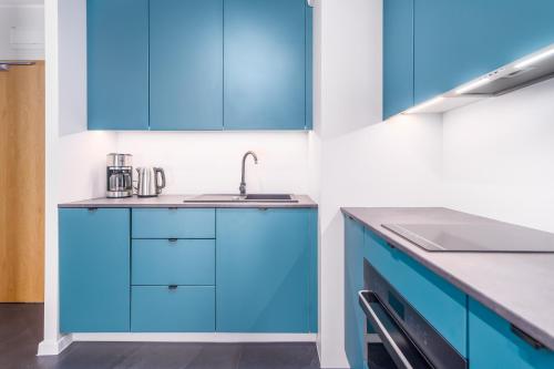 a kitchen with blue cabinets and a sink at Green Sea Apartamenty Kasprowicza in Kołobrzeg