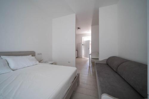 1 dormitorio con cama blanca y sofá en Beat House&Apartments, en Agrate Brianza