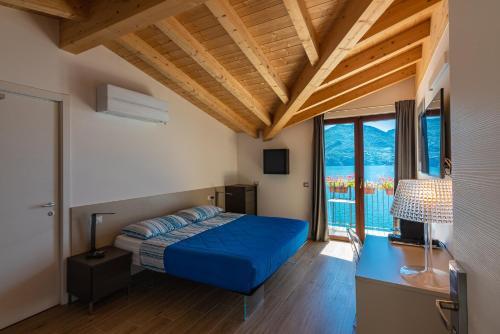 - une chambre avec un lit bleu, un bureau et des fenêtres dans l'établissement Foresteria Lago di Como, à Menaggio