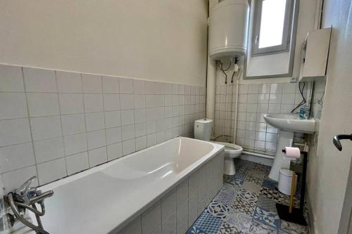 La salle de bains est pourvue d'une baignoire, d'un lavabo et de toilettes. dans l'établissement APPARTEMENT T2bis RUE BRAVARD, à Roanne