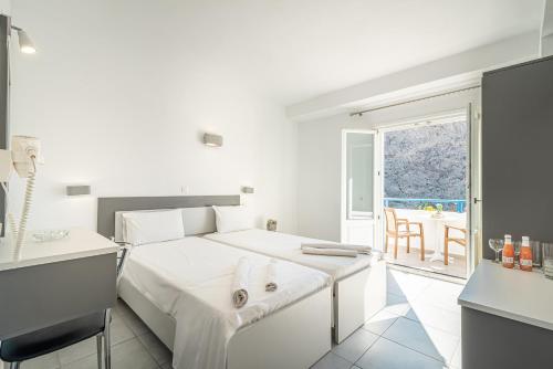 a white bedroom with a bed and a table at Marianna Hotel in Perissa