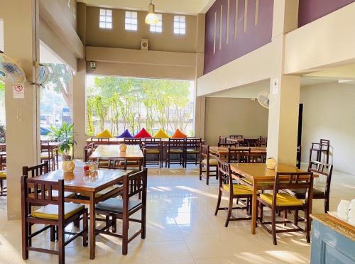 een restaurant met houten tafels en stoelen en een groot raam bij Sun Hotel in Phetchaburi