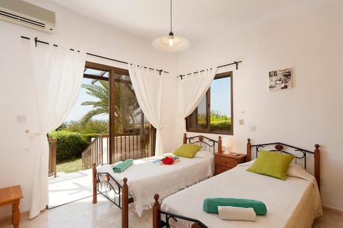 two beds in a bedroom with a balcony at Iliada Villa 4 in Peyia