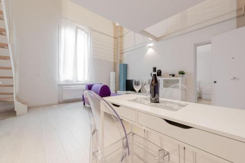 Biała kuchnia z białymi szafkami i fioletowymi krzesłami w obiekcie Realkasa Luxury S.Orsola Apartments w Bolonii
