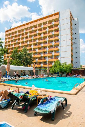 a swimming pool with people laying on lounge chairs in front of a hotel at Hotel Majestic Mamaia Half Board & All Inclusive in Mamaia