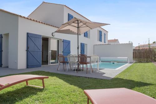 a patio with a table and chairs and an umbrella at Pierre & Vacances Premium Les Villas d'Olonne in Les Sables-dʼOlonne