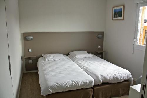 a bedroom with a large bed with white sheets at Village Vacances Passion Le Cezallier in Ardes-sur-Couze