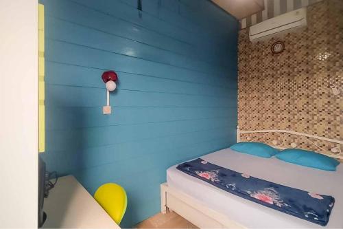 Un dormitorio con una pared azul con una cama y sillas amarillas en d'H Mansion La Rosa Syariah Sentul Mitra RedDoorz, en Bogor