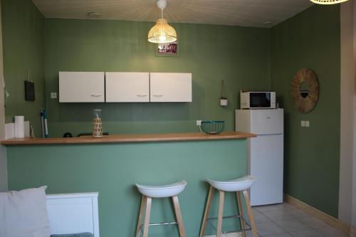 uma cozinha com 2 bancos de bar e um frigorífico em CALODURUM 2 em Chilleurs-aux-Bois