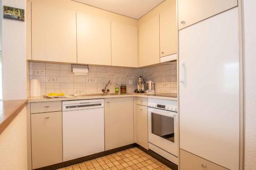 a small kitchen with white cabinets and white appliances at Ferienwohnung Schlegeli in Adelboden
