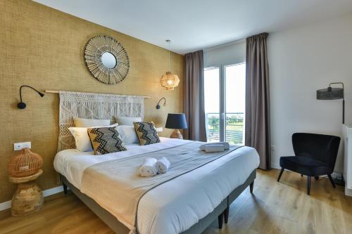 a bedroom with a large bed with a mirror on the wall at Hôtel & Spa FACE À LA MER in Merville-Franceville-Plage